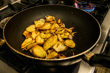 potatoes fried in oil in a frying pan with herbs for autrian food