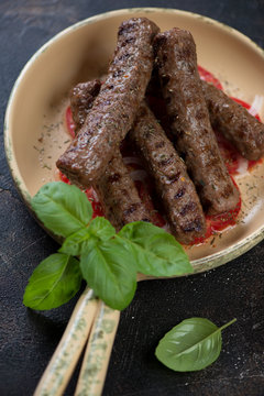 Closeup of bbq traditional balkan cevapi or skinless beef sausages in a serving pan, vertical shot, selective focus