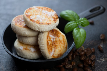 Cast-iron frying pan with curd pancakes or syrniki, horizontal shot, selective focus