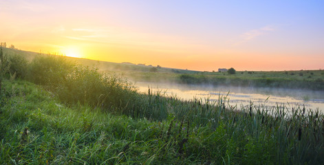 Foggy sunny landscape with river.Beautiful summer scene with rising sun.