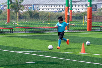 Asian boy playing football at the stadium, sports, outdoor activities