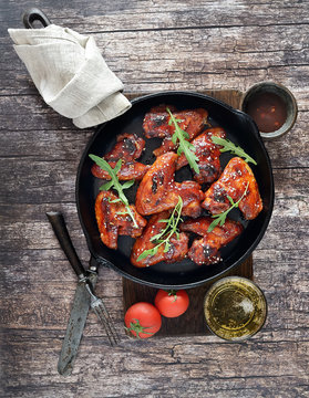 Barbecue on the grill chicken wings in a frying pan on a wooden background
