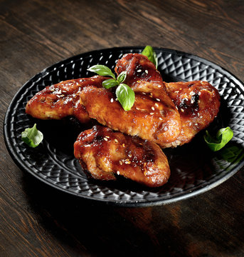 Barbecue on the grill chicken wings on a plate on a wooden background