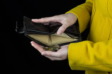 Girl pouring coins out of a purse, black background, close-up, coin