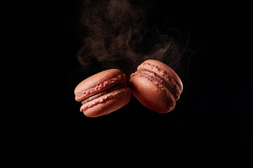 Macaron-explosie. Franse chocolade macaron met cacaopoeder tegen zwarte achtergrond