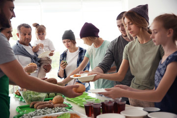 Volunteers serving food for poor people indoors