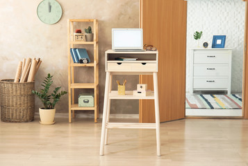 High wooden table with laptop as stand up workplace in modern interior