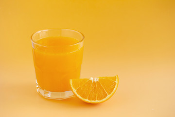 Glass of orange juice freshly squeezed on an orange background