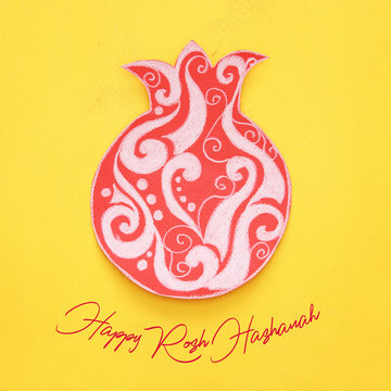 Rosh hashanah (jewish New Year holiday) concept. Traditional symbol POMEGRANATE shape cut from paper and painted.