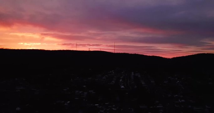 4K pan shot of a sunrise in Allentown Pennsylvania. The sun is poking over the mountains with orange and red colors filling the sky.