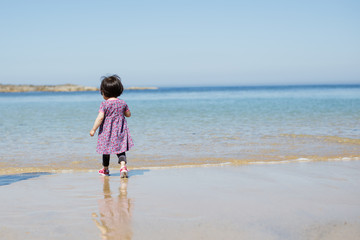 Fototapeta na wymiar baby girl wearing sunglasses running on the summer beach