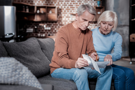 It is here. Concentrated woman sitting near her husband while pointing at document