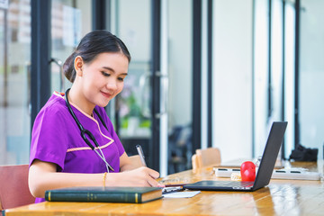 Doctor uses a laptop and writes a recipe