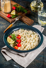 Light dietary food, couscous with tomatoes, lime and fresh herbs in dark bowl, dark blue background copy space