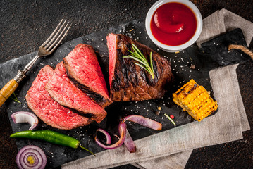 Fresh grilled beef, homemade bbq meat medium rare, on black stone cutting board, with spices, dark background, copy space top view
