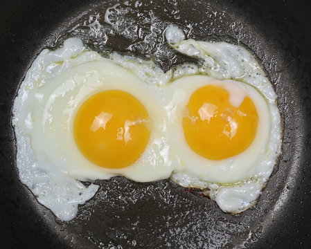 Close up two fried eggs on black pan background