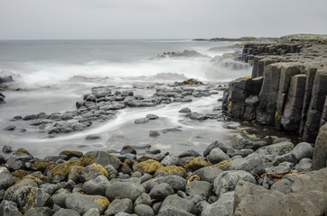 Black, basalt columns extending out into the ocean on the Chatham Islands, New Zealand. Long...