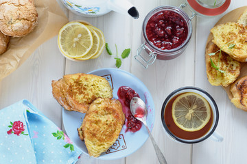 Tea with lemon, berry jam, freshly cooked toasts fried in egg mélange are ready for breakfast (view from above)