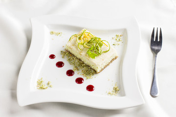 Raw food dessert cake with lemon and lime candied fruits on white plate