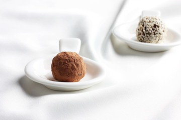 Homemade healthy raw candy truffle with sesame and chocolate on white background