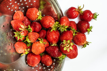 Strawberries in colander on white background