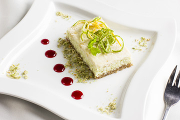 Raw food dessert cake with lemon and lime candied fruits on white plate - Powered by Adobe
