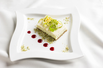Raw food dessert cake with lemon and lime candied fruits on white plate