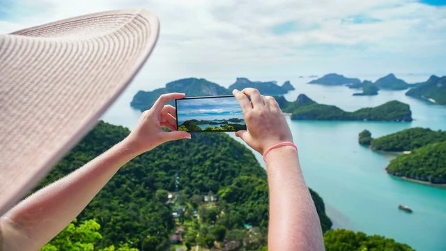 Cinemagraph of Young Female Tourist Taking Photo of Tropical Islands on Mobile Phone at Angthong National Marine Park in Thailand