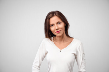 Obraz premium Pretty smiling joyfully female with dark hair, dressed casually, looking with satisfaction at camera, being happy. Studio shot of good-looking beautiful woman isolated against blank studio wall