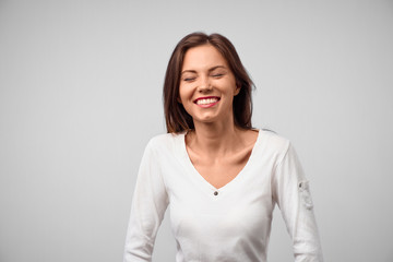 Beautiful smiling woman with clean skin, natural make-up, and white teeth on grey background