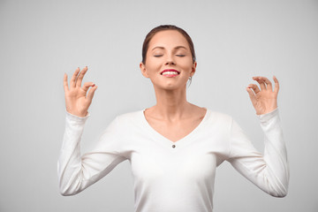 People, peace, body language and meditation concept. Cheerful brunette young female with glad expression, shows ok sign with both hands, dressd in casual white t shirt, demonstrates approval