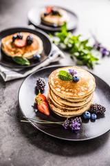 Pancakes with strawberries blackberries blueberries and lavender.