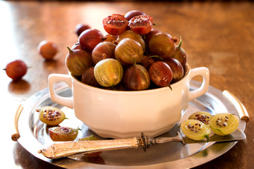 Stachelbeeren in einer weißen Schüssel mit Messer auf einem Silberteller