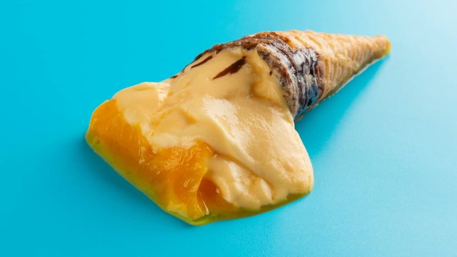 studio shoot mini mango or orange flavor ice cream cone melting and reverse on blue time lapse