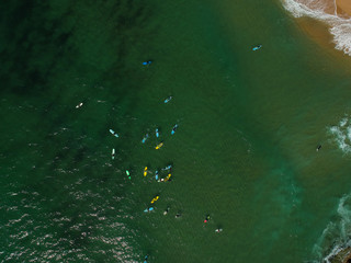Aerial view of surfers in the ocean on a summer day. Surf Spot on the Portuguese coastline. Drone shot.