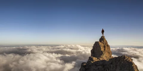 Gordijnen On the top of the world. Man on top of the mountain above the clouds. © rangizzz