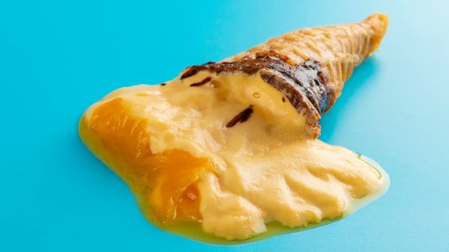 reverse studio shoot mini mango or orange flavor ice cream cone melting on blue time lapse
