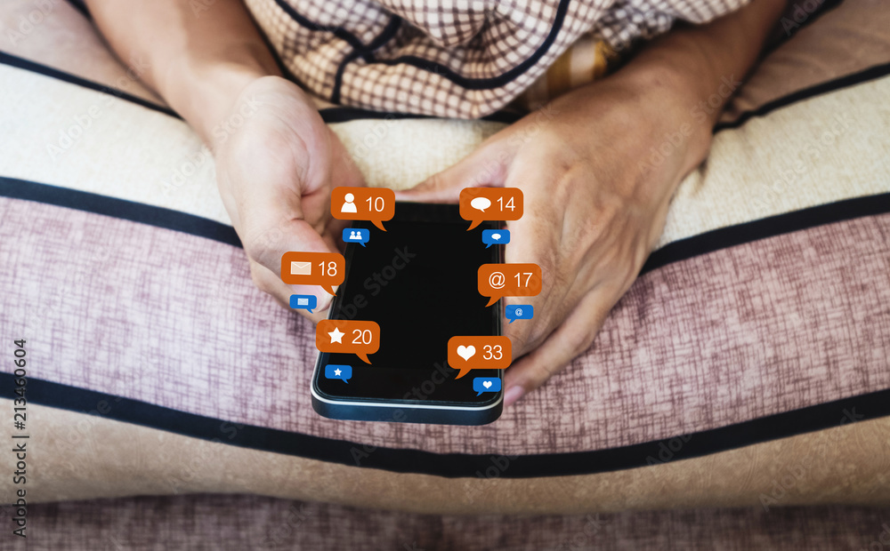 Aufkleber hand using mobile smart phone checking social media, e-mail and message on bed after waking up in th