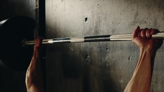 Close up shot of a muscular athlete hands bench press in a studio. Professional bodybuilder getting fit. Pumping muscles.