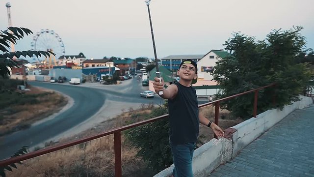 Traveler boy take a selfie portrait on selfie stick, slow motion, tourism and vacation concept.