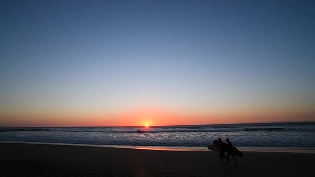 surfens on a beach at a beautiful sunrise of imsouane morocco