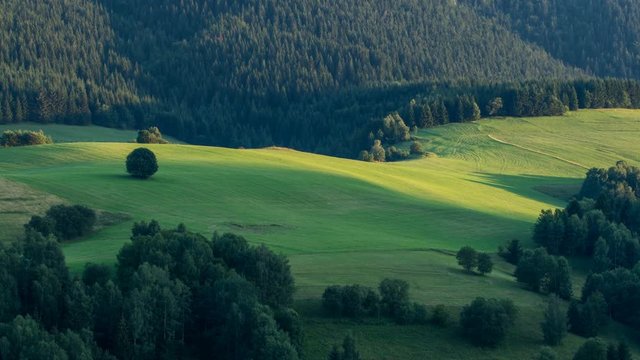 Sunset light moving over green countryside Time lapse