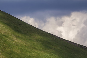 View from afar of lit by summer sun mountain Hoverla with lots of people traveling up and down by...