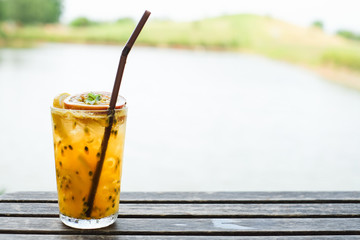Fresh passion fruit juice and haft passion fruit on top with wooden table background. Hipster style.