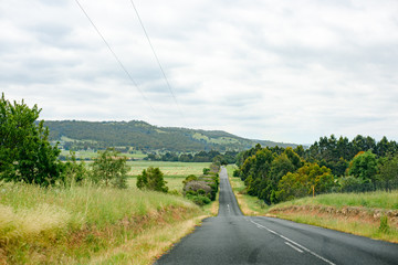 Spring country road with hay bale in farmland, in Victoria, Australia.