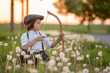 Portrait of child playing with bow and arrows, archery shoots a bow at the target.