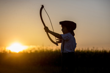 Portrait of child playing with bow and arrows, archery shoots a bow at the target.