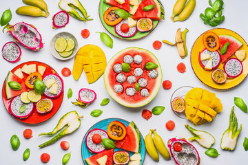Flat lay of summer various colorful sliced tropical fruits and berries in plates and bowls  on white  background, top view.  Clean and healthy lifestyle  background