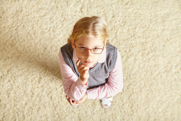 school age girl with glasses on a carpet