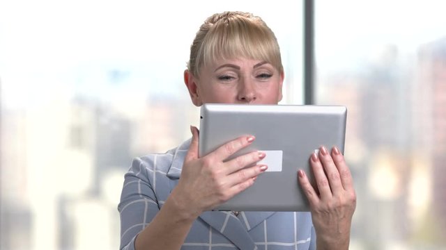 Happy senior woman with tablet in office. Elegant smiling middle aged businesswoman with tablet computer.
